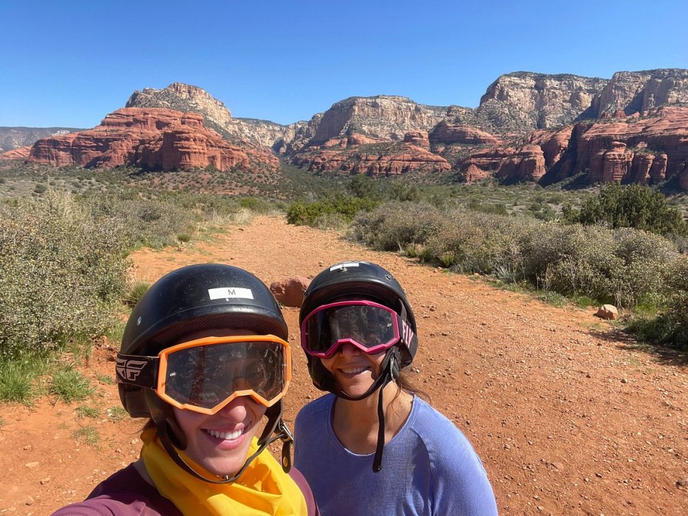 a couple of tourist wearing helmets and goggles standing on top of a mountain