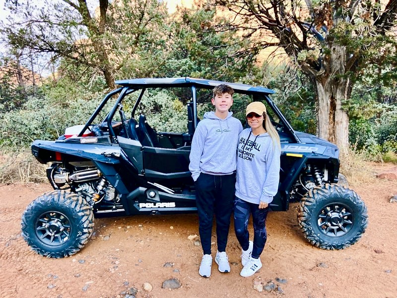 a person standing next to a UTV with desert greenery behind them