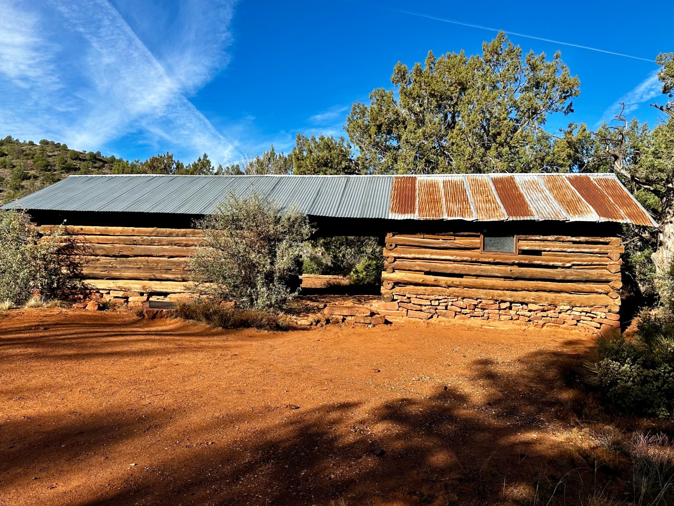 Lush red rock formations, winding dusty trails, vibrant desert flora, golden sunlight filtering through trees, breathtaking sunset casting shadows on the landscape.