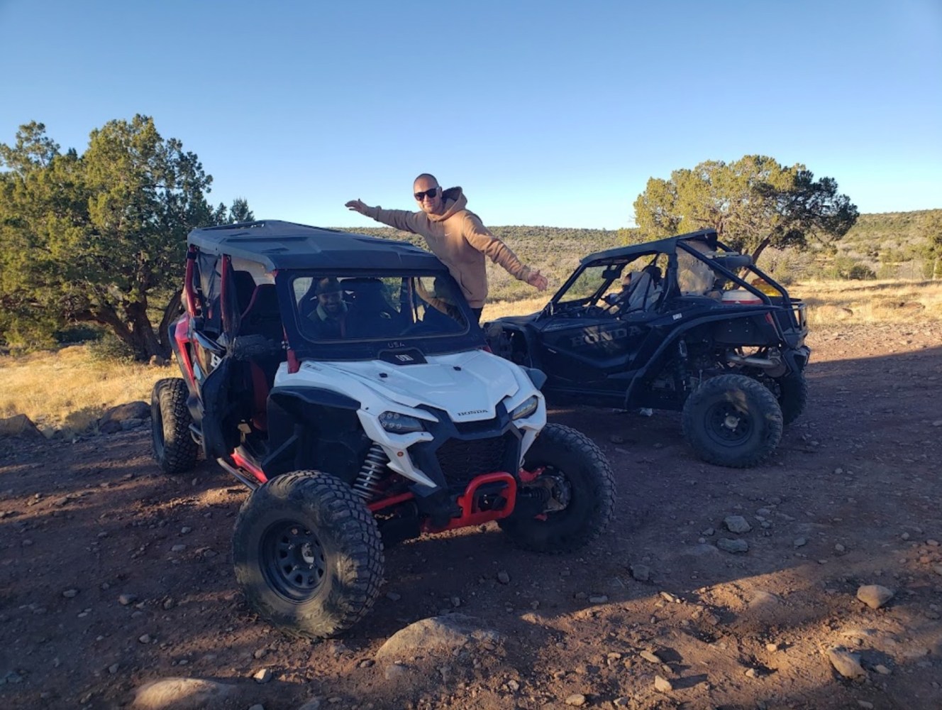 a man riding on the back of a UTV driving down a dirt road