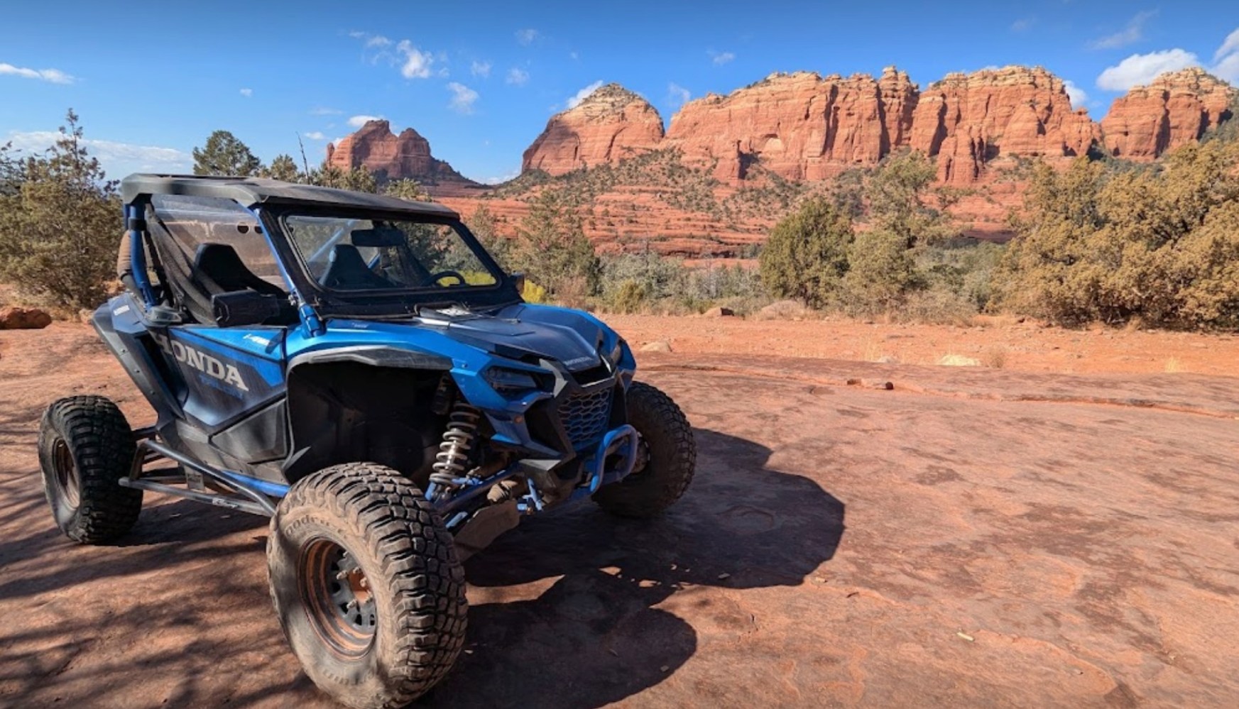 The composition emphasizes the scale and grandeur of the Sedona landscape, with an off-road vehicle serving as the focal point of this immersive, adventure-filled scene.